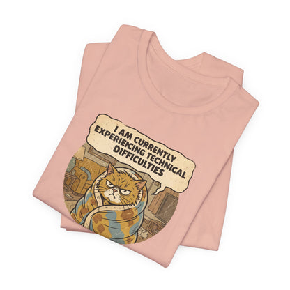 Pink t-shirt with graphic of a grumpy cat wrapped in a blanket saying "I AM CURRENTLY EXPERIENCING TECHNICAL DIFFICULTIES".