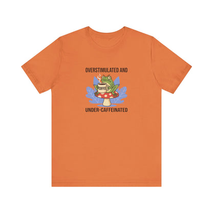 T-shirt with frog wearing glasses, holding coffee cup, with text "Overstimulated and Under-caffeinated".