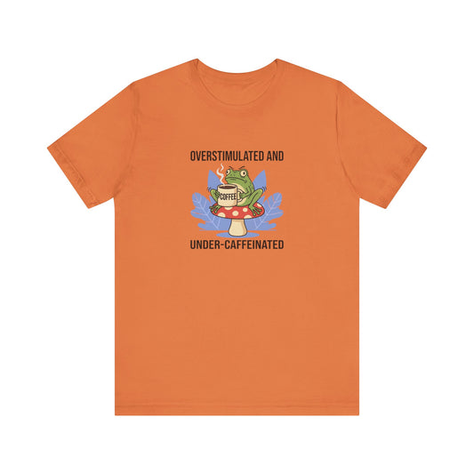 T-shirt with frog wearing glasses, holding coffee cup, with text "Overstimulated and Under-caffeinated".