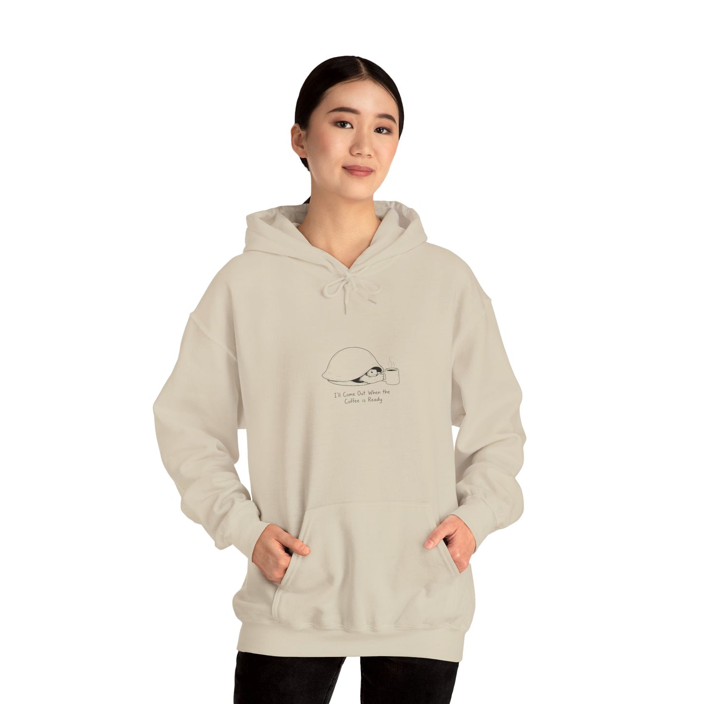 Woman wearing a beige hoodie with a coffee mug and text graphic.