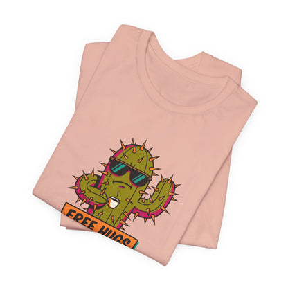 Folded pink t-shirt with cartoon cactus wearing sunglasses holding coffee, text "FREE HUGS".