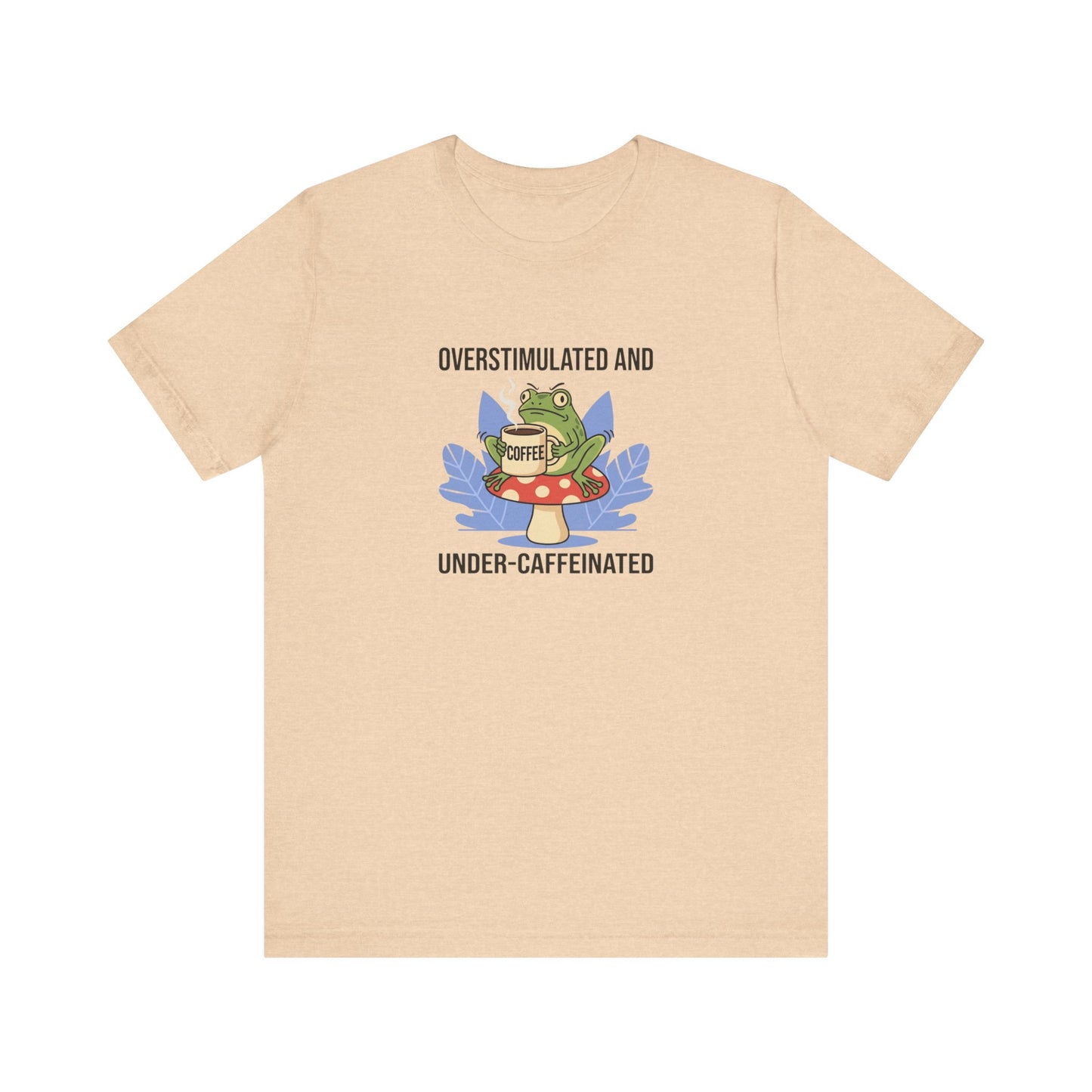 T-shirt graphic with frog on mushroom, holding coffee cup, text "Overstimulated and Under-caffeinated".