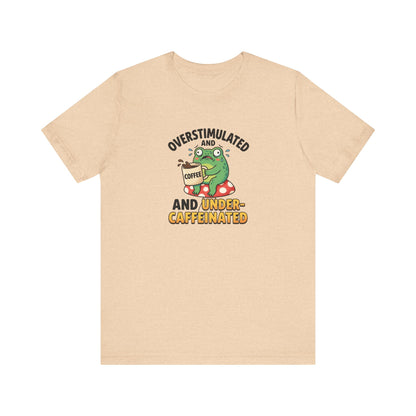 T-shirt graphic of a frog on a mushroom, holding coffee, with text "overstimulated and caffeinated".