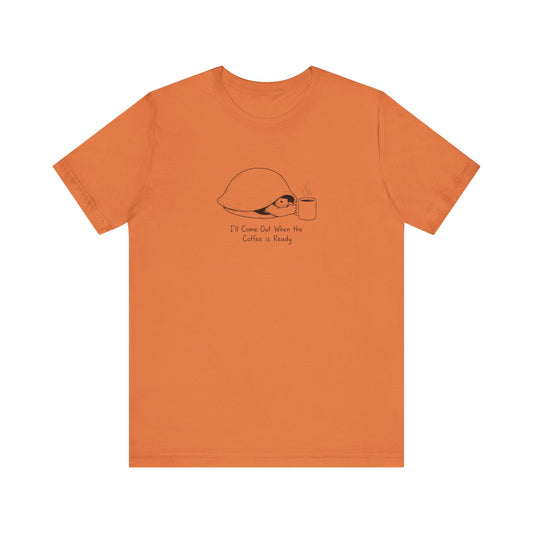Orange t-shirt with a turtle and coffee cup graphic and text.