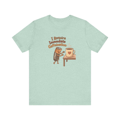 Cartoon coffee cup character on a mint green t-shirt with text "I Require Immediate Caffeination."