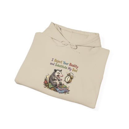 Beige hoodie with opossum and alarm clock graphic, "I Reject Your Reality and Substitute My Bed" text.