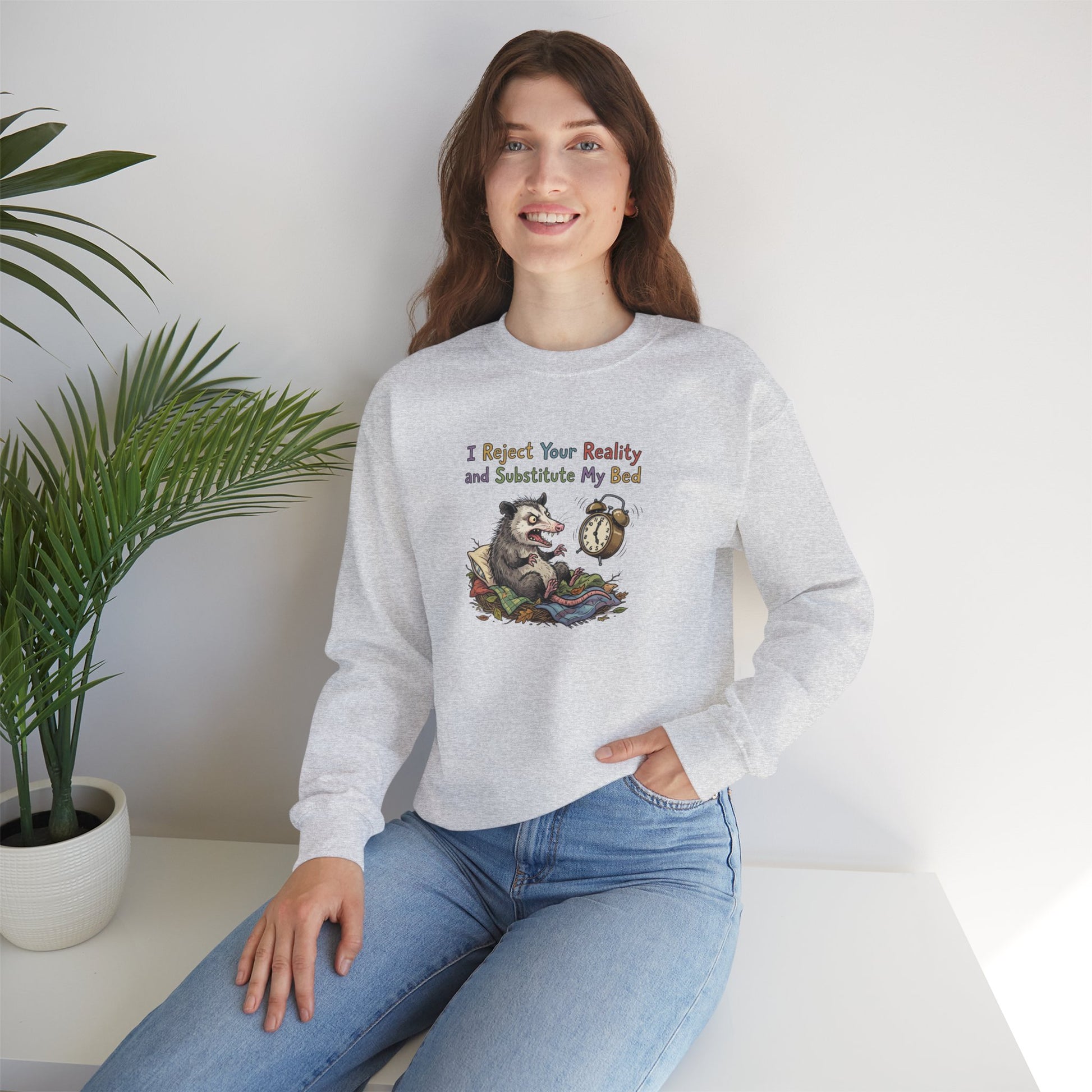 Woman wearing a grey sweatshirt with an opossum alarm clock illustration and text.