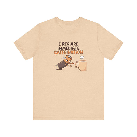 T-shirt with cartoon battery reaching for coffee cup, text "I REQUIRE IMMEDIATE CAFFEINATION".