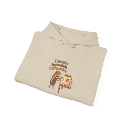 Beige hoodie with cartoon battery and coffee cup graphic reading "I require immediate caffeination."