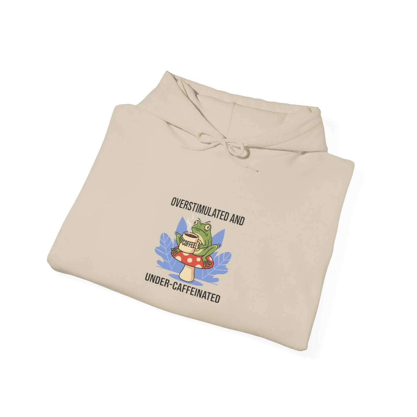 Cream hoodie with a frog on a mushroom and text "OVERSTIMULATED AND UNDER-CAFFEINATED COFFEE".