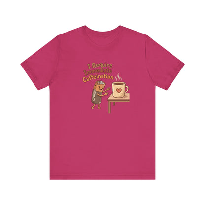 T-shirt with cartoon character holding a coffee mug, text "I Require Immediate Caffeination."
