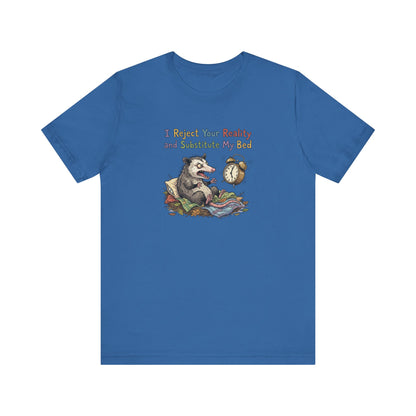 Blue t-shirt with possum in bed and text "I Reject Your Reality and Substitute My Bed".